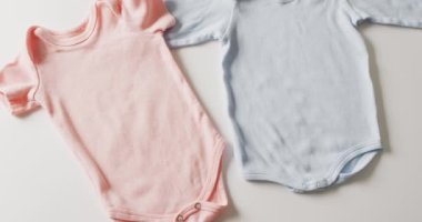 Mavi ve pembe bebeğin yakın çekim videosu beyaz arka planda büyüyor. Bebek, giysi, kumaş, doku ve malzeme konsepti.