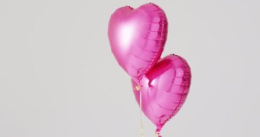 Beyaz zemin üzerinde yüzen iki parlak pembe kalp şeklinde balon videosu, fotokopi alanı ile. Sevgililer Günü, aşk, aşk ve kutlama konsepti.