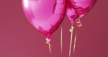 Pembe arka planda yüzen dört parlak pembe kalp şeklinde balonun videosu. Sevgililer Günü, aşk, aşk ve kutlama konsepti.