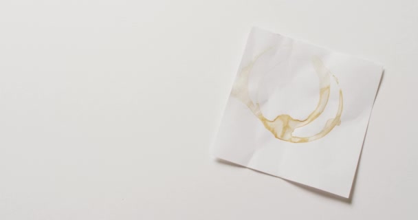 在白底上贴有咖啡杯环污迹的纸片的视频关闭 纹理和材料概念 — 图库视频影像