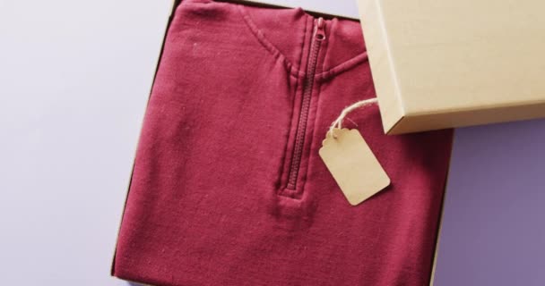 Filmik Bliska Czerwonego Swetra Metką Pudełku Fioletowym Tle Koncepcja Odzieży — Wideo stockowe