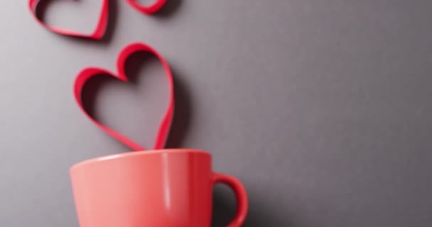 コピースペースのある灰色の背景に 赤いマグカップと浮遊赤いハート型のビデオ バレンタインデー ロマンス 愛とお祝いのコンセプト — ストック動画