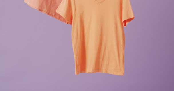 在紫色背景上挂着橙色T恤衫的特写视频 质地和材料概念 — 图库视频影像