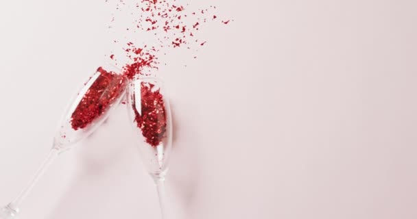 Video Two Champagne Glasses Spilling Red Glitter Confetti White Background — Stock Video