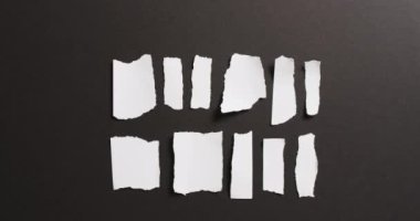 Siyah arka planda birden fazla beyaz kağıt parçasının yakın çekim videosu. Kağıt, yazı, doku ve malzeme kavramı.