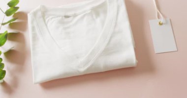 Pembe arka planda beyaz katlanmış tişört videosu. Giyim, moda, perakende, kumaş, doku ve malzeme konsepti.