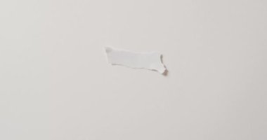 Beyaz zemin üzerinde fotokopi alanı olan yırtık kağıt parçasının yakın çekim videosu. Kağıt, yazı, doku ve malzeme kavramı.