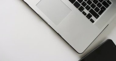 Kahve, defter ve akıllı telefonlu dizüstü bilgisayarın beyaz arka planda fotokopi alanı olan videosu. Teletıp, tıbbi hizmetler, sağlık hizmetleri ve sağlık farkındalığı kavramı.