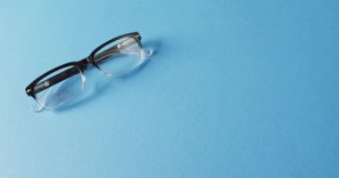 Mavi arkaplanda fotokopi alanı olan bir çift gözlük videosu. Sağlık hizmetleri, sağlık hizmetleri ve sağlık farkındalığı kavramı.