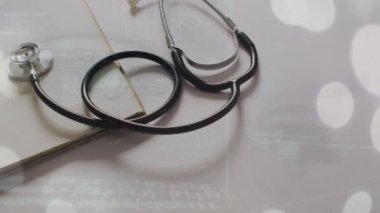 Stetoskop üzerinden ışık noktaları ve veri işleme animasyonu ve beyaz zemin üzerinde not defteri. Küresel tıp, sağlık ve dijital arayüz kavramı dijital olarak üretilen video.