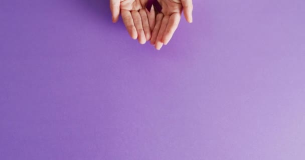 紫色の背景に認識リボンをコピースペースで追加または追加保持している手のビデオ 医療サービス 精神衛生意識の概念 — ストック動画