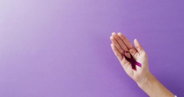 Mor arkaplanda fotokopi alanı olan el ele tutuşmanın ekleme veya farkındalık kurdelesi videosu. Sağlık hizmetleri, sağlık hizmetleri ve zihinsel sağlık farkındalığı kavramı.