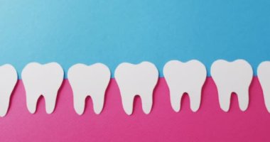 Mavi arka planda pembe sakızlı beyaz dişlerin fotokopi çekilen videosu. Sağlık hizmetleri, sağlık hizmetleri ve diş sağlığı farkındalığı kavramı.