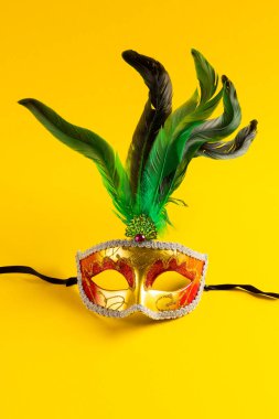 Renkli Mardi Gras karnaval maskesinin kompozisyonu sarı arka planda fotokopi alanı ile. Parti, kutlama ve karnaval konsepti.