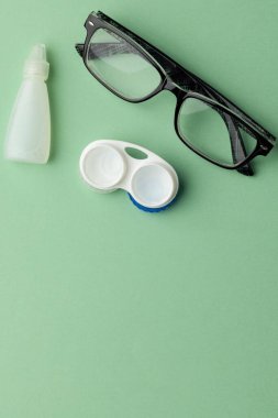 Kontakt lensli gözlüklerin dikey hali ve yeşil arkaplanda fotokopi alanı olan solüsyon. Sağlık hizmetleri, sağlık hizmetleri ve sağlık farkındalığı kavramı.