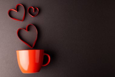 Kırmızı kalp, kırmızı bardaktan yükselen koyu gri arka planda, fotokopi alanı ile şekillenir. Sevgililer günü, aşk, aşk ve kutlama konsepti.