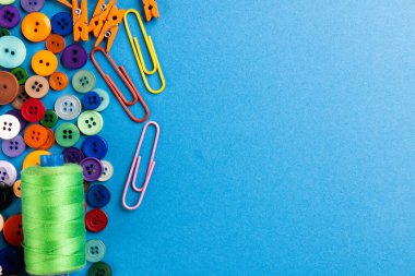 Mavi arkaplanda fotokopi alanı olan dikiş ekipmanlarının bileşimi. Ulusal zanaat ayı, dikiş, kıyafet ve dikiş konsepti.