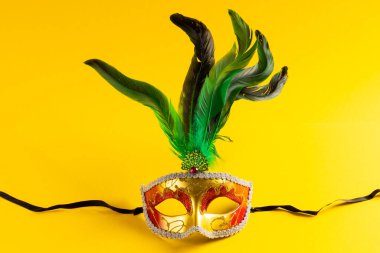 Renkli Mardi Gras karnaval maskesinin kompozisyonu sarı arka planda fotokopi alanı ile. Parti, kutlama ve karnaval konsepti.