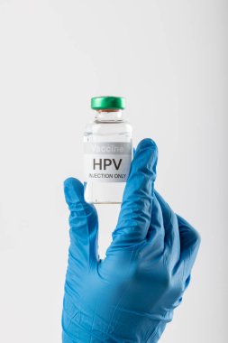 Doktorun eldivenli elinin beyaz arka planda fotokopi aletiyle HPV aşı tüpünü tutuşu. Tıp, sağlık hizmetleri, sağlık hizmetleri ve sağlık farkındalığı kavramı.