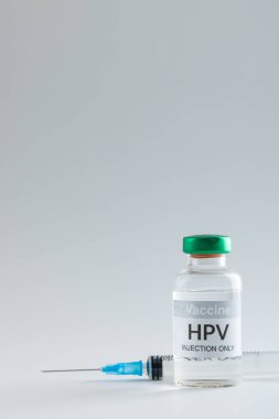 Hpv aşı şişesi ve şırınganın dikey bileşimi gri arka planda fotokopi alanı ile. Tıp, sağlık hizmetleri, sağlık hizmetleri ve sağlık farkındalığı kavramı.