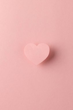 Pembe kalp şeklinin dikey hâli ve arka planda fotokopi alanı olan pembe bir gölge. Sevgililer günü, aşk, aşk ve kutlama konsepti.