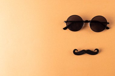 Sahte bıyık ve turuncu arka planda fotokopi alanı olan gözlükler. Sahte bıyık günü, parti, kutlama ve kostüm konsepti..