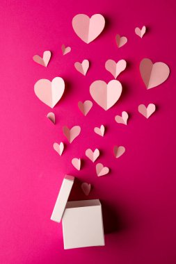 Beyaz hediye kutusunun dikey hâli. Pembe arka planda beyaz kalpleri fotokopi alanı ile serbest bırakıyor. Sevgililer günü, aşk, aşk ve kutlama konsepti.