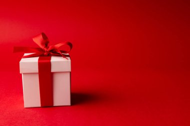 Kırmızı kurdeleli beyaz hediye kutusu, kırmızı arka planda fotokopi alanı. Sevgililer günü, aşk, aşk ve kutlama konsepti.