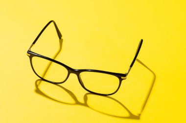 Yüksek açılı bir çift gözlük ve sarı arkaplanda fotokopi alanı olan bir gölge. Sağlık hizmetleri, sağlık hizmetleri ve sağlık farkındalığı kavramı.