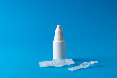 Mavi arka planda tuz çözeltisi kapsülleri ve damlatıcı şişesinin bir kopyası. Sağlık hizmetleri, sağlık hizmetleri ve sağlık farkındalığı kavramı.