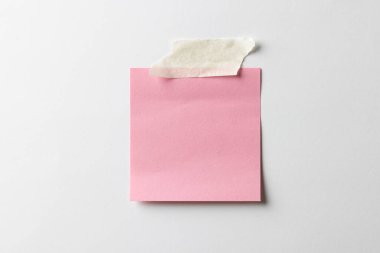 Üzerinde bant olan pembe yapışkan not ve beyaz arkaplan üzerine kopyalama alanı. Soyut kağıt dokusu arka plan ve iletişim konsepti.