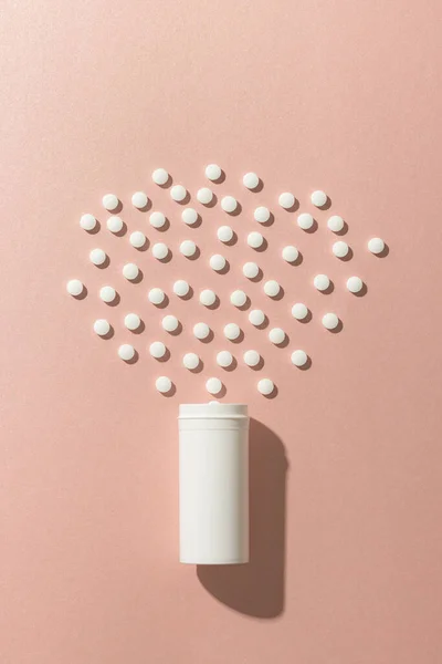 Vertical composition of white pill box and white pills on pink background with copy space. Medicine, medical services, healthcare and health awareness concept.