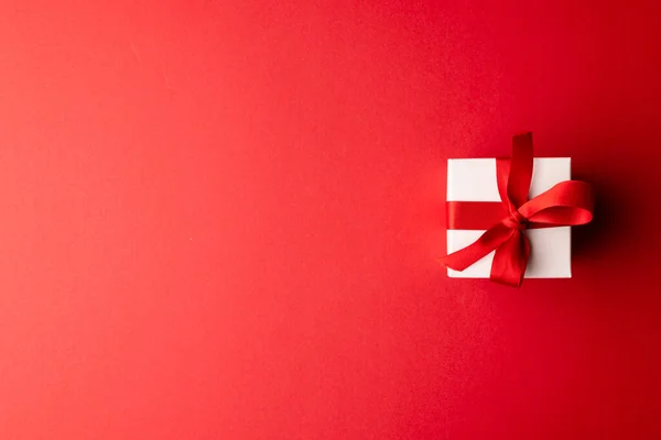 コピースペースのある赤い背景に 赤いリボンで結ばれた白いギフトボックスのオーバーヘッド バレンタインデー ロマンス お祝いのコンセプト — ストック写真