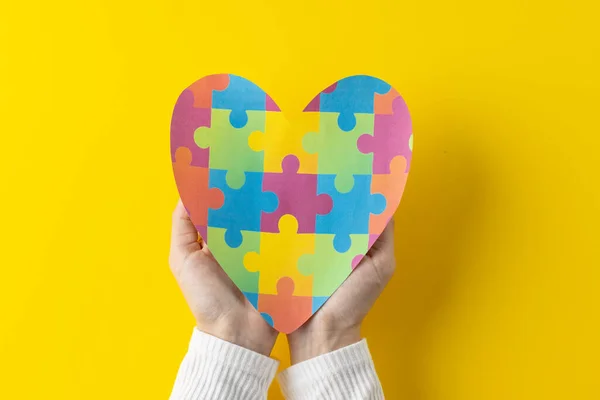 stock image Composition of hands holding jigsaw puzzle heart on yellow background with copy space. Medical services, healthcare and health awareness concept.