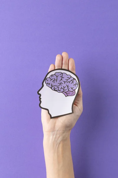 紫色の背景に紫色の脳と頭のシルエットを保持する手の垂直 コピースペースと 医療サービス 精神衛生意識の概念 — ストック写真