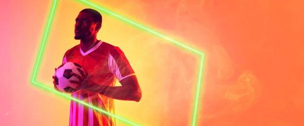 非裔美国男性足球运动员在烟熏的背景下 用明亮的长方形托着球 复制空间 霓虹灯 发光和抽象 — 图库照片