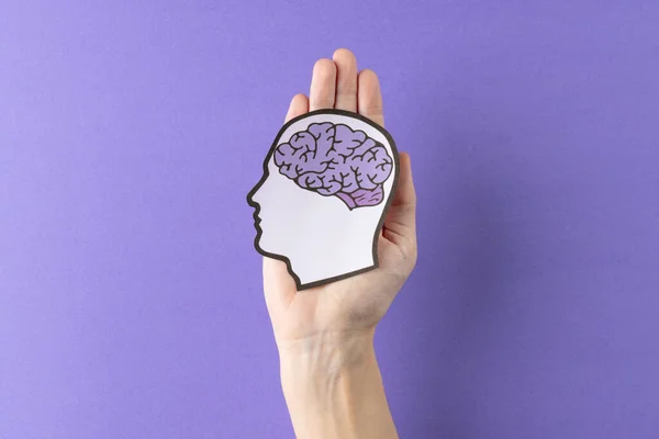 紫色の背景に紫色の脳で頭のシルエットを保持する手の構成 コピースペースと 医療サービス 精神衛生意識の概念 — ストック写真