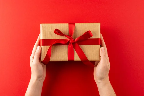 Overhead Hands Holding Gift Brown Paper Red Ribbon Red Background —  Fotos de Stock