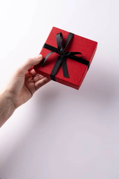 手の垂直は コピースペースと白い背景に 黒いリボンで結ばれた赤いギフトボックスを与えます バレンタインデー 誕生日 ロマンス お祝いのコンセプト — ストック写真