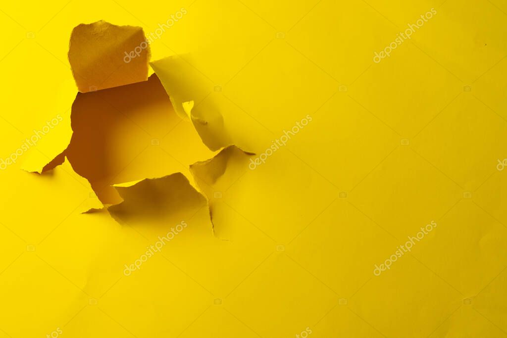 Ripped up piece of yellow paper with copy space on yellow background. Abstract paper texture background and communication concept.