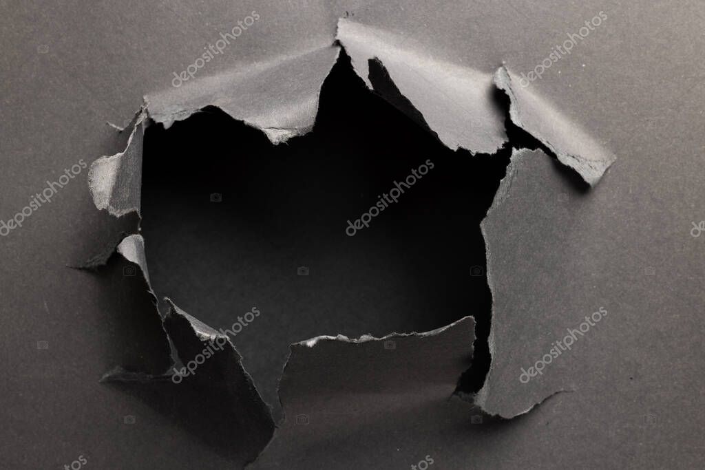 Ripped up piece of black paper with copy space on black background. Abstract paper texture background and communication concept.