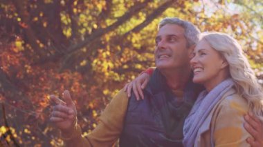 Parktaki beyaz bir çiftin üzerindeki şekillerin animasyonu. Yaşam tarzı, doğa ve sonbahar konsepti dijital olarak oluşturulmuş video.