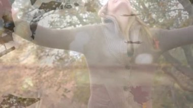 Parkta beyaz bir kadının üzerine düşen yaprak ve şekillerin animasyonu. Yaşam tarzı, doğa ve sonbahar konsepti dijital olarak oluşturulmuş video.