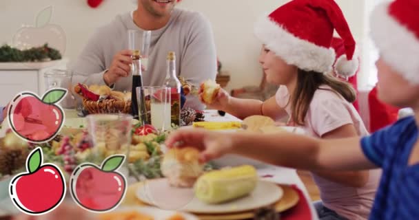 Animacja Jabłek Nad Białą Rodziną Kapeluszach Mikołaja Podczas Świątecznej Kolacji — Wideo stockowe