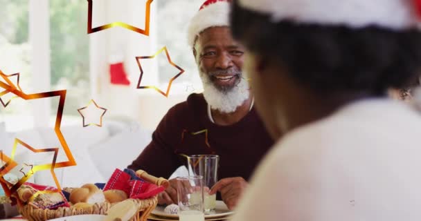 Animacja Gwiazd Nad Afrykańską Amerykańską Rodziną Kapeluszami Mikołaja Świątecznej Kolacji — Wideo stockowe