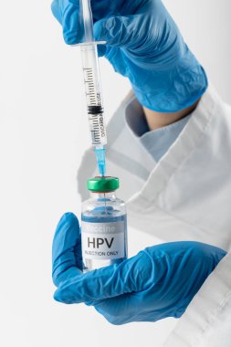 Doktorun eldivenli ellerinin dikey hali HPV aşı şişesinden şırıngayı dolduruyor, beyaz üzerine kopyalama alanı koyuyor. Tıp, sağlık hizmetleri, sağlık hizmetleri ve sağlık farkındalığı kavramı.
