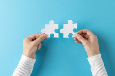 Beyaz yapboz parçalarını tutan el kompozisyonu mavi arka planda kopyalama alanı olan. Sağlık hizmetleri, sağlık hizmetleri ve sağlık farkındalığı kavramı.