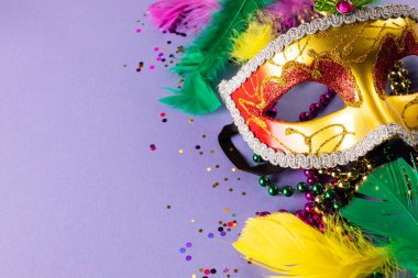 Mavi arka planda renkli mardi gras boncukları, tüyler ve karnaval maskesi. Parti, kutlama ve karnaval konsepti.