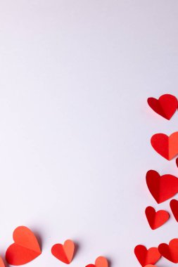 Kırmızı kağıttan kalbin dikey görüntüsü beyaz arkaplanda fotokopi alanı ile şekilleniyor. Sevgililer günü, aşk, aşk ve kutlama konsepti.