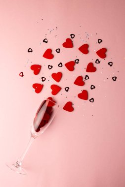 Şampanyaların dikey yansıması kırmızı kalp şekilleri açık pembe arka planda fotokopi alanı ile birlikte. Sevgililer günü, aşk, aşk ve kutlama konsepti.